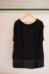 Chaleco negro tejido a mano en dos agujas con hilado 100% baby alpaca, ligeramente oversize, de hombros anchos y cuello tipo bote, con puntos calados en frente y espalda y tajos a los lados en el bajo.