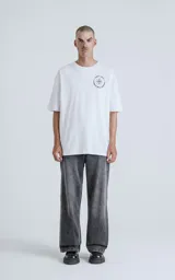 Remera blanca de algodón con estampa sublimada de una figura femenina sosteniendo un salvavidas con la frase "Chill Bitch Trust Karma" y el texto "The Wheel of Fortune". Corte oversize y cuello redondo.