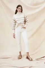 Suéter de punto color crema con rayas horizontales marrones, cuello alto y mangas largas.