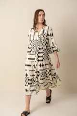 Vestido midi color crema con estampado geométrico en negro, corte evasé, cuello en V y mangas 3/4 acampanadas.
