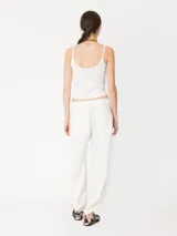 Pantalón largo de lino color blanco, de corte amplio y tiro alto. Presenta recortes en delantero y espalda, bolsillos escondidos al frente y bolsillos ojal en la parte posterior. Lleva jareta con lazo para ajustar y bordado marcario JCH en el delantero.