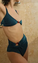 Top de bikini marrón con textura en zig zag, breteles regulables, copas con relleno y detalle de piedra decorativa de resina en el centro.