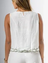 Musculosa blanca con bordado floral verde en el frente, cuello redondo y corte holgado.