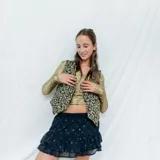 Chaleco corto color crema con escote en V, sisa redonda y cierre delantero con botones.