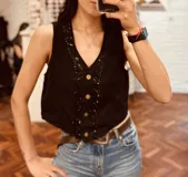 Chaleco color beige de pana con botones y ribete de cuentas negras.