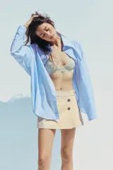 Falda pantalón color beige de tiro medio con diseño cruzado y cierre con botones. Cuenta con bolsillos falsos en la parte delantera y trasera, y cierre lateral con cremallera oculta.
