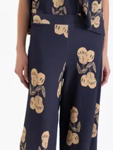 Pantalón de tejido de punto acanalado color azul marino con estampado de cerezas en tono beige. Presenta cintura elastizada y piernas amplias.