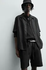 Bermuda negra de lino con calce relajado. Presenta cintura elástica ajustable con cordón, bolsillos frontales y un bolsillo trasero de plastrón.