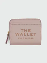 Billetera compacta Marc Jacobs de cuero color lila con cierre de cremallera y logo estampado en el frente.
