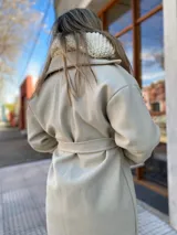 Tapado color beige con cuello solapa, corte recto, largo hasta la rodilla y cinturón de lazo.