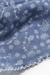 Pañuelo triangular de tela celeste con estampado de flores blancas y borde festoneado. Se ata en la nuca.