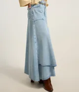 Pollera midi de jeans celeste claro con diseño de recortes y bajo irregular deshilachado. Presenta cintura con trabillas y cierre frontal.