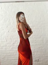 Vestido largo de microtul estampado en tonos naranja y marrón, con escote drapeado, breteles finos y tajo lateral.