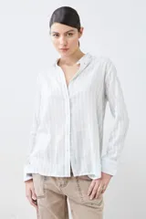 Camisa oversize celeste y blanca a rayas verticales, con cuello mao y mangas largas con puños abotonados.