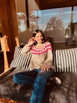 Sweater marrón tejido a mano en mohair con cuello redondo y diseño con motivos geométricos en colores blanco, rosa y celeste.
