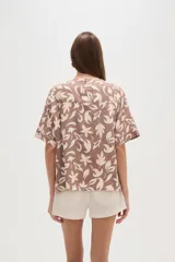 Blusa marrón con estampado de hojas color crema, cuello en V y mangas cortas. Corte holgado.