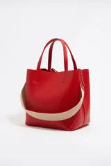 Bolso tote negro de cuero vacuno con doble asa corta y correa de tela extraíble. Interior con tres compartimentos y bolsillo con cremallera. Logo metálico de la marca en el frente.