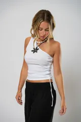 Top blanco de morley fino, con un solo hombro, ojales a ambos costados y cordones regulables que permiten ajustar el largo.