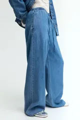 Pantalón denim celeste de corte holgado, con cintura elástica, cordón ajustable, bolsillos laterales y piernas anchas.