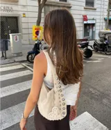 Bolso hobo color crema con tachas plateadas y cierre con botón magnético.