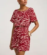 Enterito corto de poliéster con estampado abstracto en tonos borgoña y blanco. Tiene mangas cortas, escote redondo, cierre en la espalda, elástico en la cintura y lazo para ajustar.