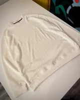 Buzo blanco de punto con cuello redondo y mangas largas. Diseño minimalista y corte clásico.