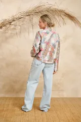 Bomber estampada con motivos florales y de aves en tonos pastel, con cuello mao, cierre frontal con botones dorados, bolsillos laterales con solapa y puños elásticos.