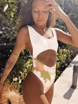 Entero de baño con recorte en la panza y en la espalda. La parte superior es de terciopelo blanco y la parte inferior es de lycra estampada con flores en tonos naranja y verde.