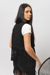 Chaleco negro de gamuza sintética con flecos y tachas plateadas.