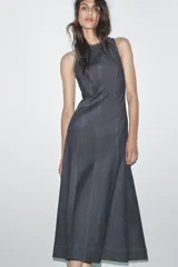 Vestido midi de denim azul oscuro, con cuello redondo y sin mangas. Presenta costuras a contraste y cierre trasero con cremallera oculta.