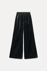 Pantalón de terciopelo negro de tiro medio con cintura elástica, bolsillos laterales ocultos y pierna ancha.