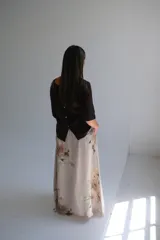 Falda larga de lino color beige con estampado floral en tonos pastel, corte amplio y cintura elastizada con cinturón de soga trenzada.