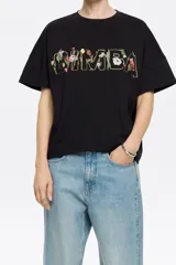 Camiseta negra de corte boxy con escote redondo, manga corta recta y logo bordado con flores.
