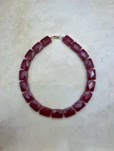 Collar corto de piedras facetadas rectangulares en rojo, blanco, negro y turquesa, con detalles dorados.