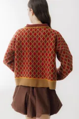Sweater de punto color beige con diseño de rombos marrones, cuello polo con botones y mangas largas abullonadas.