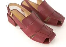 Sandalia de cuero color borgoña, con punta cuadrada y tiras anchas entrecruzadas. Tiene talón abierto con pulsera ajustable y hebilla metálica. El taco es ancho y mide 4 cm.