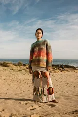 Sweater tejido a mano de lana merino, con cuello a la base y puños. Diseño a rayas horizontales en tonos celeste, marrón, naranja y amarillo.