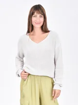 Buzo de tejido de punto color beige claro, con escote en V y manga larga.