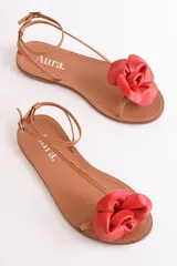 Sandalias bajas de cuero color suela, con tiras finas y aplique de flor roja en el empeine.