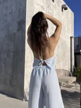 Top celeste a rayas verticales blancas, con escote halter y múltiples lazos frontales.