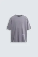 Camiseta gris de corte holgado, cuello redondo y manga corta. Estampado con la frase "Live in Style Everyday" en el frente.