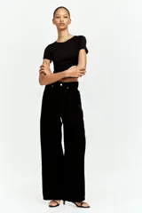 Remera cropped negra de punto elástico, entallada con costuras fruncidas en un hombro y a ambos lados de la cintura para crear un leve efecto drapeado.