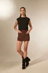 Minifalda marrón de gamuza sintética con tiro alto y detalles de tachas doradas a lo largo de los costados y bolsillos delanteros.