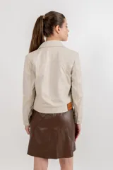 Campera corta de cuero ovino color borgoña, estilo jeanera, con cuello clásico, bolsillos con solapa y cierre frontal con broches metálicos.