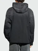 Campera negra con capucha y cierre frontal con cremallera. Tiene puños elásticos y un pequeño parche con el logo de la marca en el pecho.