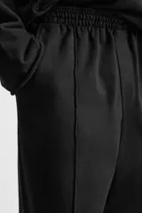 Pantalón wide fit confeccionado en tejido de algodón con interior en rizo, color negro. Cintura elástica ajustable con cordón interior, bolsillos frontales y detalle de bolsillo trasero de vivo. Perneras con costura frontal y efecto lavado.