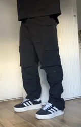 Pantalón cargo negro de corte recto con múltiples bolsillos con solapa y botón a presión.