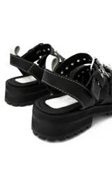 Sandalias negras de cuero con hebillas plateadas, suela track y costuras blancas.