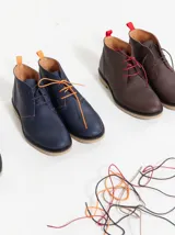 Botas acordonadas marrones de cuero, con suela de goma y costuras rojas. Incluye un par de cordones adicionales.