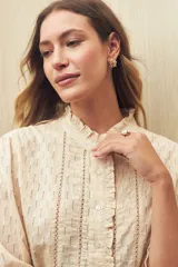 Camisa blanca de manga 3/4 confeccionada en algodón liviano con diseño calado y detalles de encaje en el frente. Cuello con volados.